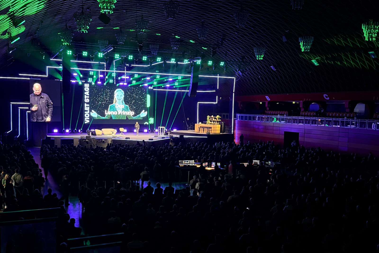 Blick von den Rängen auf die volle Violet Stage, auf der Leinwand steht Das Lena Prinzip