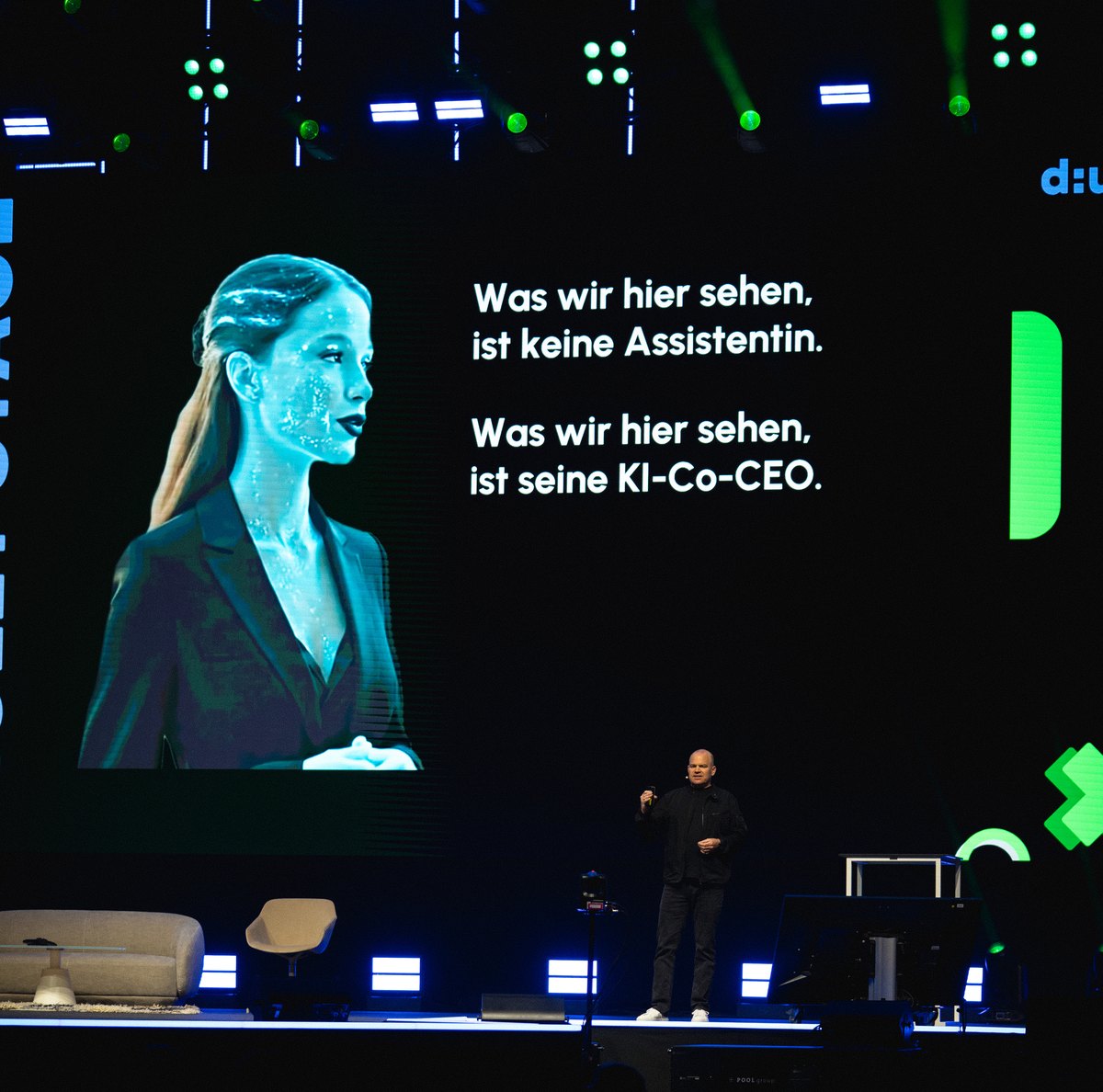 Christian Steiger on a dark stage, behind him a large screen with the sentence about the AI co-CEO