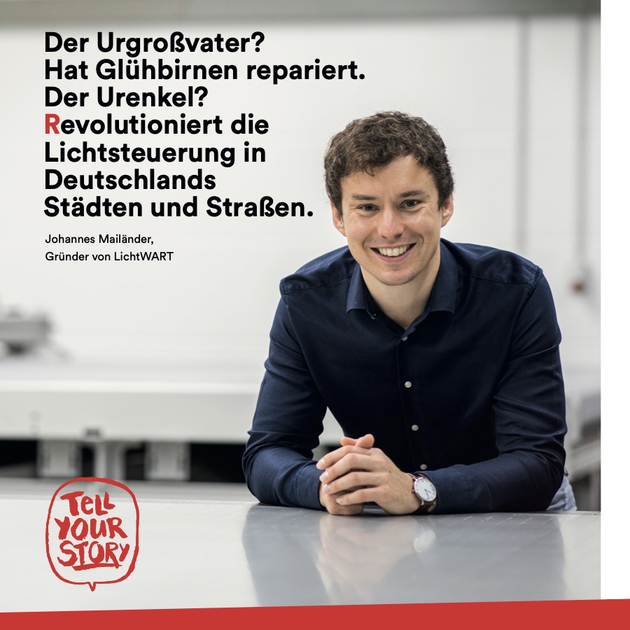 Tell-Your-Story-Motiv: Johannes Mailänder, Gründer von LichtWART, lächelnd am Tisch, daneben: „Der Urgroßvater? Hat Glühbirnen repariert. Der Urenkel? Revolutioniert die Lichtsteuerung in Deutschlands Städten und Straßen.“