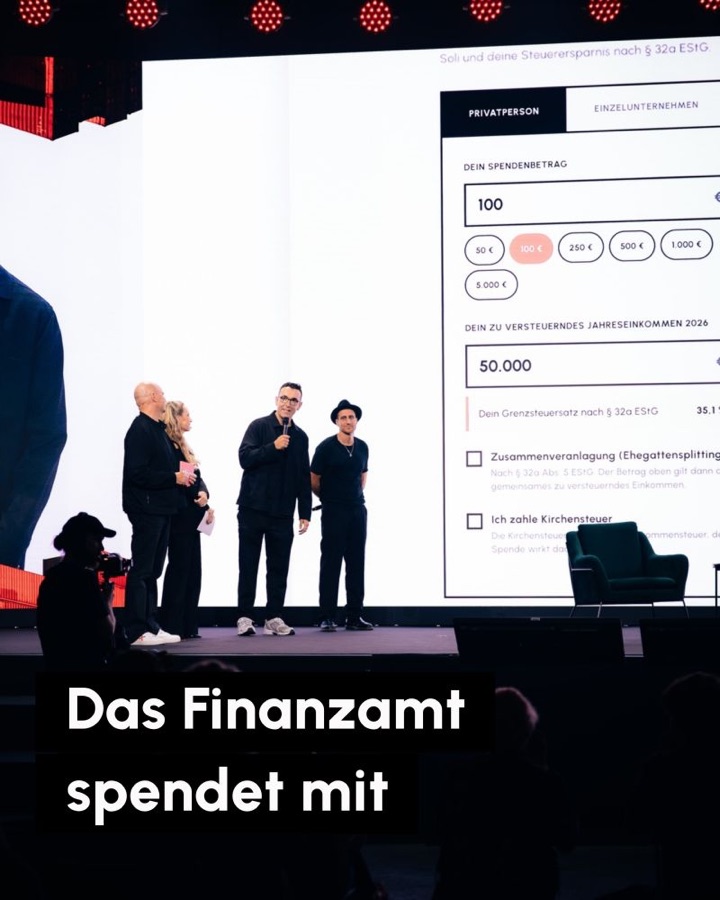 Christian Steiger mit Michael Fritz und zwei weiteren Personen auf der Festivalbühne vor dem Spendenrechner auf der Leinwand. Schrift: Das Finanzamt spendet mit.