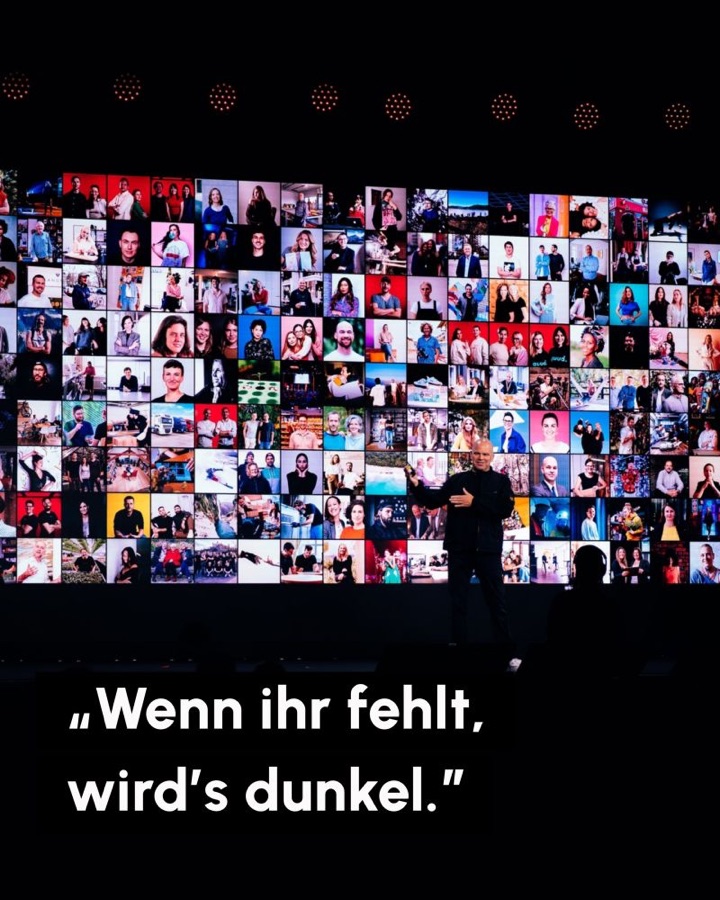 Christian Steiger auf der Bühne des Lexware Festivals vor einer Wand aus Hunderten Porträts von Selbstständigen. Schrift: Wenn ihr fehlt, wird's dunkel.