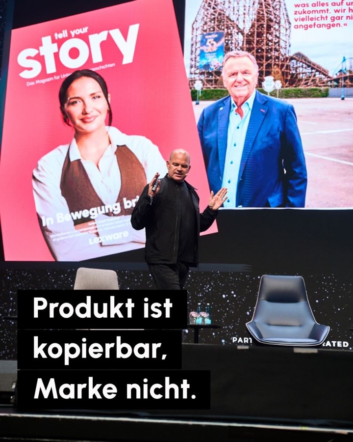 Christian Steiger auf der Bühne der Black Forest Space in Offenburg vor großen Leinwänden mit dem Tell-Your-Story-Magazin. Schrift: Produkt ist kopierbar, Marke nicht.