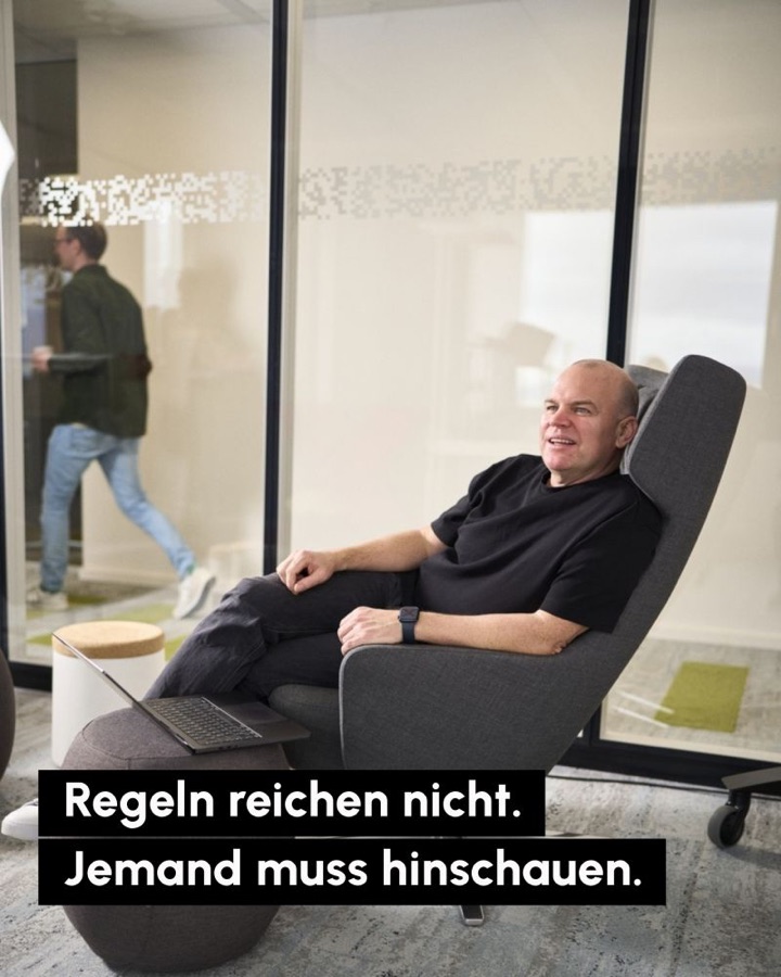 Christian Steiger lehnt entspannt in einem grauen Sessel im Büro, Laptop auf dem Hocker. Schrift: Regeln reichen nicht. Jemand muss hinschauen.