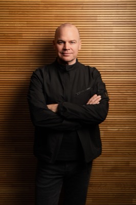 Christian Steiger, Porträt vor Holzwand, verschränkte Arme